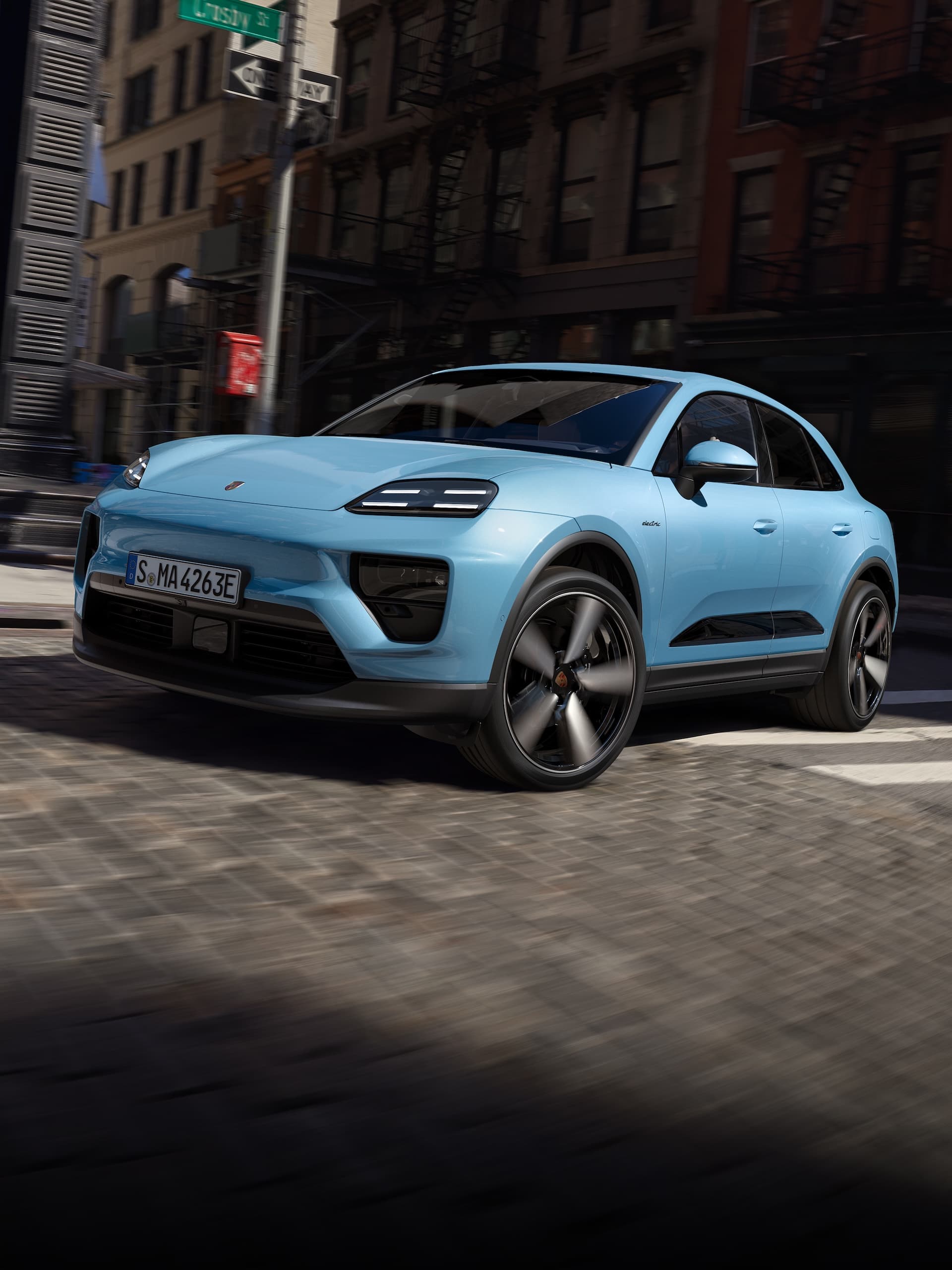Un Porsche totalmente eléctrico Macan conduciendo por una carretera en un escenario urbano.